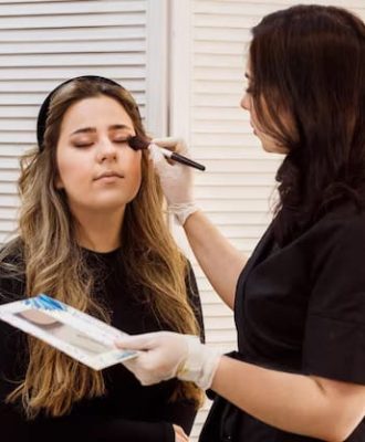 makeup-artist-applying-makeup-her-client-beautician-cabinet_148669-1189